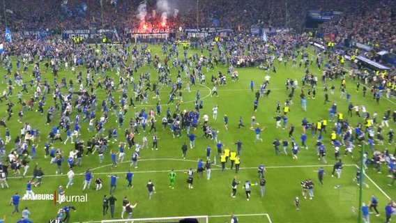 Fans auf dem Spielfeld in einem Stadion. © Screenshot 