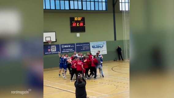 Standbild aus einem Handy-Video: Eine Handball-Mannschaft fällt sich in die Arme nach einem gewonnenen Pokalspiel in einer Turnhalle. © Screenshot 
