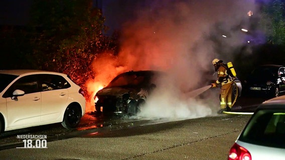 Ein Feuerwehrmann löscht ein brennendes Auto. © Screenshot 