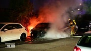 Ein Feuerwehrmann löscht ein brennendes Auto. © Screenshot 