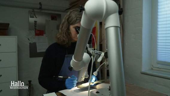 Archäologin Sara Beuster schaut durch ein Mikroskop. © Screenshot 
