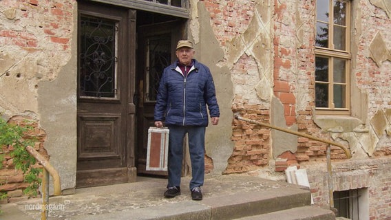 Ein älterer Mann steht vor einem alten Gutshaus. © Screenshot 
