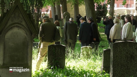 Eine Personenegruppe auf einem alten jüdischen Friedhof. © Screenshot 