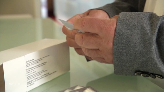 Hände halten eine Blisterpackung Tabletten, daneben eine Medikamenten-Packung. © Screenshot 
