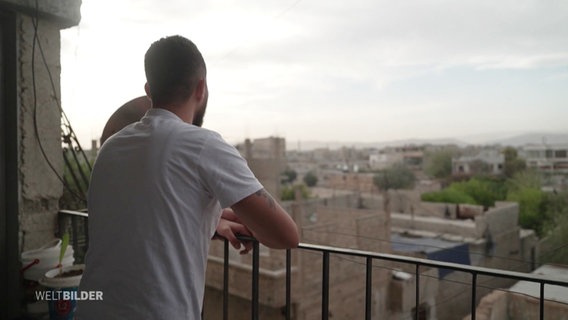 Ein junger Syrer blickt von einem Balkon auf die Stadt. © Screenshot 