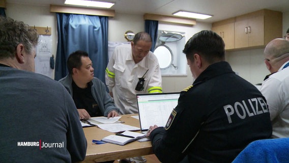 Beamte der Wasserschutzpolizei bei der Sichtung von Unterlagen auf einem Schiff. © Screenshot 