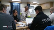 Beamte der Wasserschutzpolizei bei der Sichtung von Unterlagen auf einem Schiff. © Screenshot 