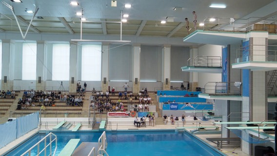 Innenansicht der Neptun-Schwimmhallein Rostock mit Tribüne und Sprungtürmen © Screenshot 