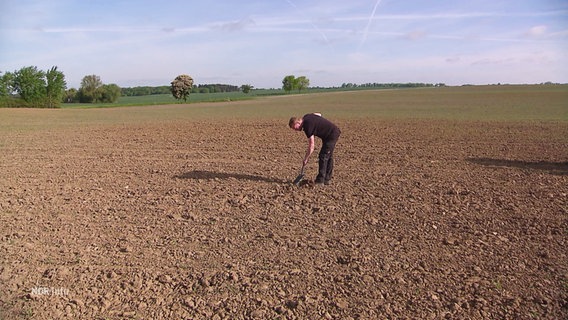 Ein Mann gräbt auf einem Feld, der Boden ist trocken. © Screenshot 