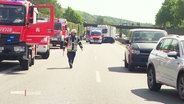Feuerwehrwagen, Autos und Rettungskräfte stehen auf der Fahrbahn der A25. © Screenshot 
