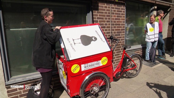 Ein rotes Lastenrad, links und rechts daneben stehen Personen. © Screenshot 