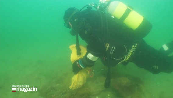 Ein Taucher unter Wasser mit einem gelben Müllbeutel. © Screenshot 