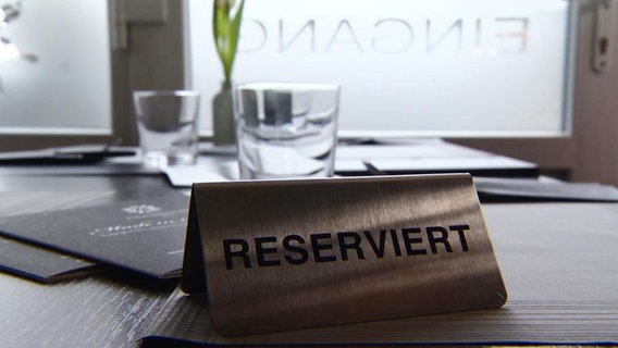 Auf einem Tisch in einem Restaurant steht ein "Reserviert"-Schild.  