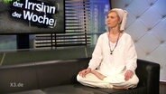 Foodbloggerin und Diät-Beraterin Kirstin Warnke sitzt in einem weißen Gewand mit Turban auf einer schwarzen Couch.  