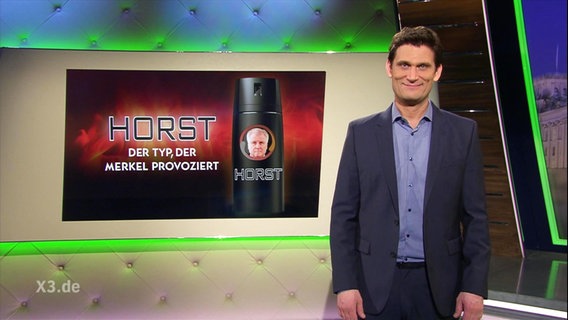 Hinter Christian Ehring ist ein Bild zu sehen von einem Deo namens "Horst", ein Duft, der Merkel provoziert.  