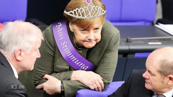 Angela Merkel mit Diadem und Schärpe.  