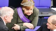 Angela Merkel mit Diadem und Schärpe.  