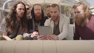 Der dänische Sänger Rasmussen (Zweiter von Links in der vorderen Reihe), sitzt mit seiner Band im Tuktuk und singt.  