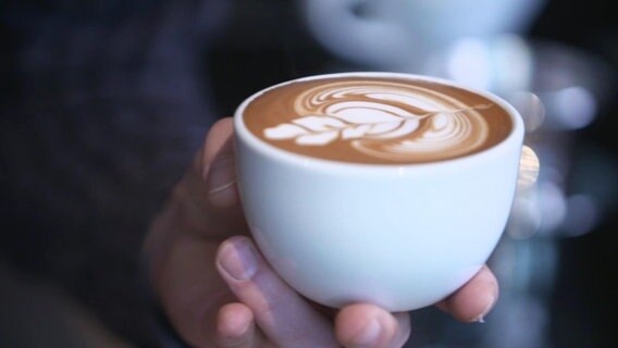 Eine mit Milchschaum kunstvoll verzierte Tasse Kaffee.  