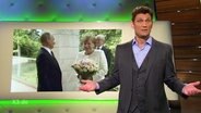 Christian Ehring moderiert extra 3, im Hintergrund ein Bild von Merkel und Putin.  