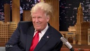 Trump in einer Talkshow mit verwuschelten Haaren.  