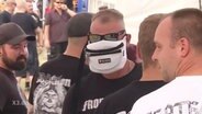 Ein Neonazi mit einem Hipbag als Sichtschutz im Gesicht  