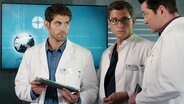 Dr. Ahrend, Dr. Bähr und ein weiterer Kollege beraten sich. © NDR 