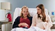 Zwei schwangere  Frauen liegen nebeneinander in einem Krankenhausbett.  