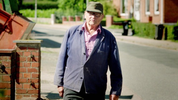 Ein Mann mit Mütze geht eine Straße entlang.  