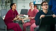 Vivienne Kling (Jane Chirwa), Julia Berger (Mirka Pigulla) und Elias Bähr (Stefan Ruppe) sitzen im Aufenthaltsraum. © Screenshot 