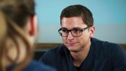 Elias Bähr (Stefan Ruppe) spricht mit einer Patientin.  