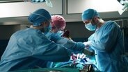 Drei Ärzte, die gemeinsam operieren. © NDR 