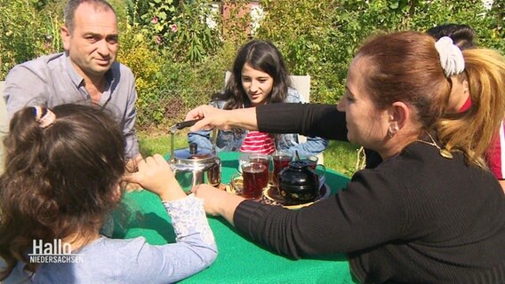 Familie Yossef sitzt im Kleingarten und trinkt Tee.  