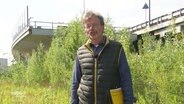 Person mit einem Aktenordner unterm Arm steht unter einer Brücke, die im Nirgendwo endet  