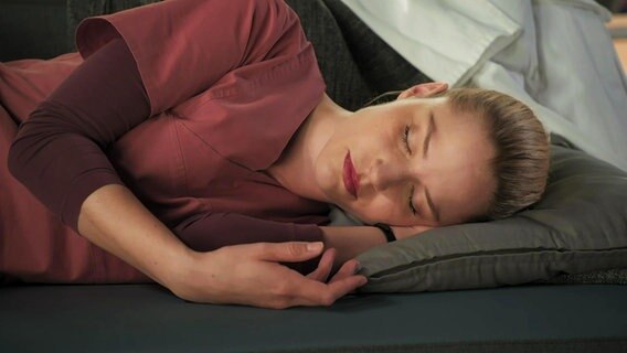 Julia Berger (Mirka Pigulla) schläft erschöpft auf dem Sofa ein.  