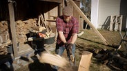 Ein Mann hackt Holz.  