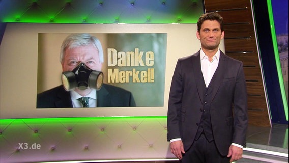 Hinter Christian Ehring ist ein Mann mit Gasmaske zu sehen und neben ihm steht geschrieben: "Danke Merkel!"  