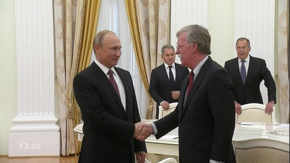 Putin schüttelt dem US-Sicherheitsbeauftragten die Hand.  