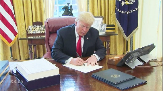 Donald Trump sitzt an seinem Schreibtisch  
