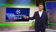 Christian Ehring gestikuliert. Hinter ihm auf Leinwand "Champions Leak".  