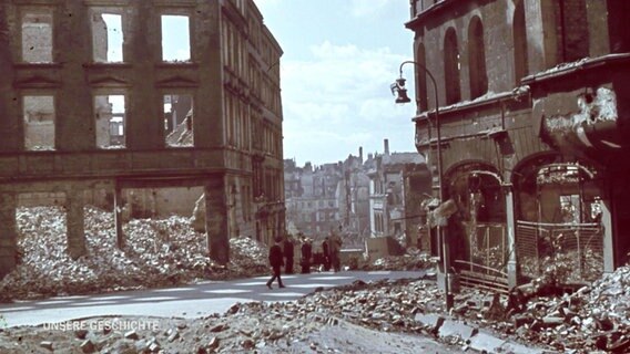 Menschen gehen durchs zerstörte Hamburg nach dem Bombenhagel im Zweiten Weltkrieg.  