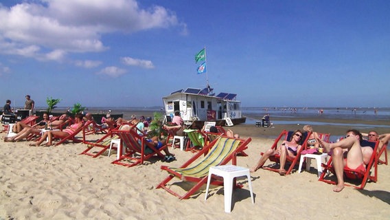 Menschen in Liegestühlen am Strand von Cuxhaven.  