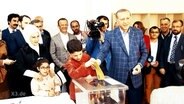 Erdogan wirft einen Wahlschein ein.  