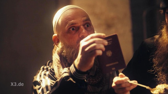 Ein Deutsche IS-Kämpfer hält seinen Pass hoch.  