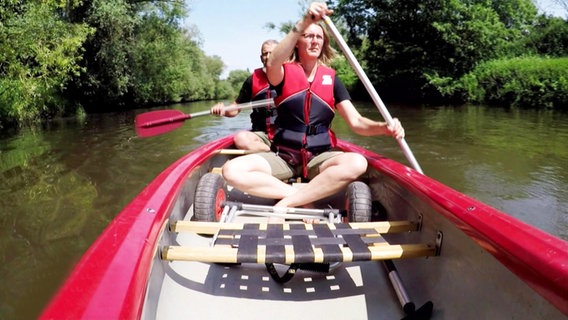 Ein Mann und eine Frau paddeln in einem roten Kanu auf der Ihme.  