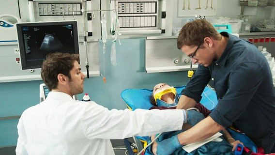 Dr. Niklas Ahrend (Roy Peter Link) und Dr. Elias Bähr (Stefan Ruppe) behandeln die verletzte Lilly Bartosch (Emilia von Heiseler). © Screenshot NDR 