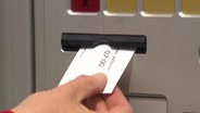 Hand nimmt Kurtaxen-Karte aus einem Automaten.  