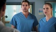 Dr. Niklas Ahrend (Roy Peter Link) und Julia Berger (Mirka Pigulla) schauen erschrocken einen Patienten an. © NDR 