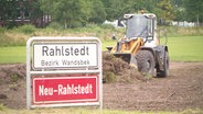 Bauarbeiten für den Victoria Park: Ein Bagger steht neben dem Ortsschild "Rahlstedt". © NDR 
