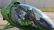 Zwei Personen, die in einem kleinen Hellikopter sitzen. © NDR 